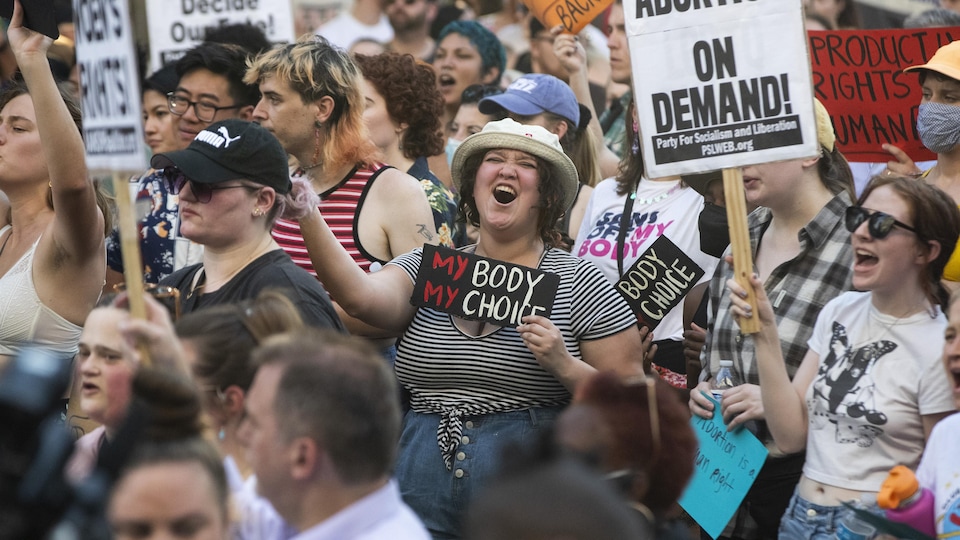 Dans une foule, une manifestante tient une pancarte où on peut lire : « mon corps, mon choix ».