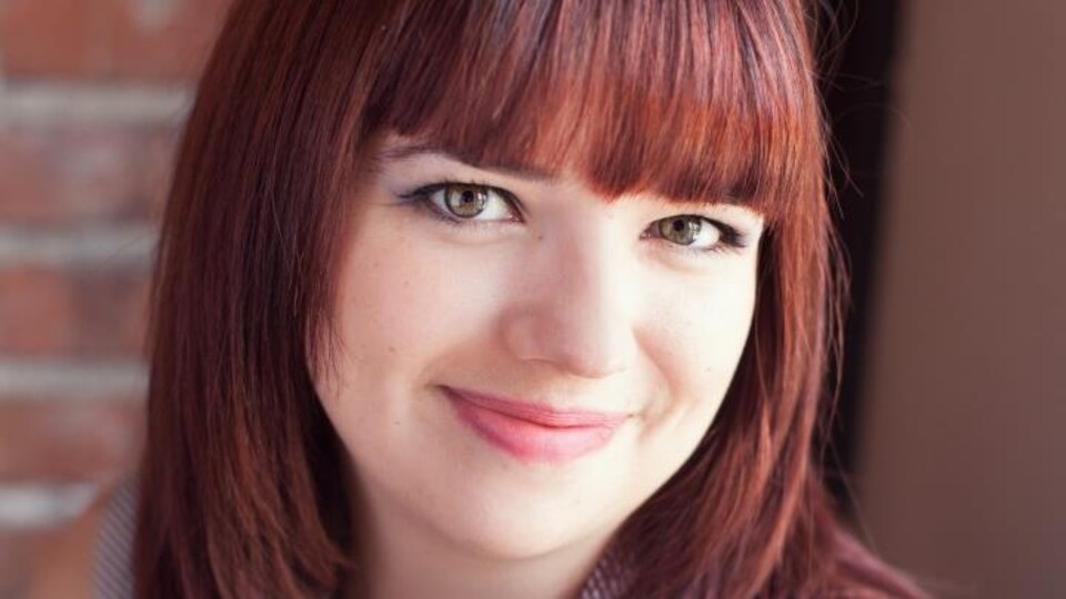 La jeune femme sourit en regardant devant elle.