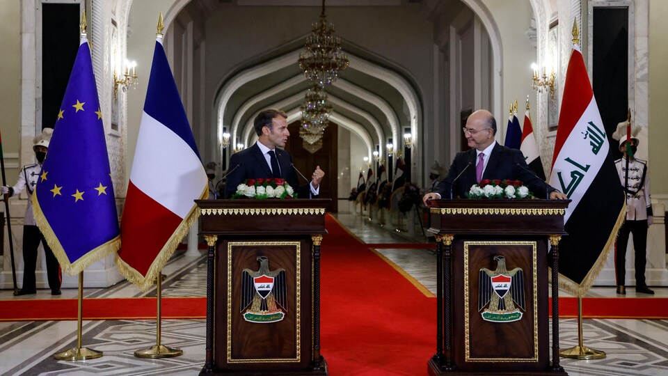 Le président français et le président irakien derrière des lutrins se regardent.