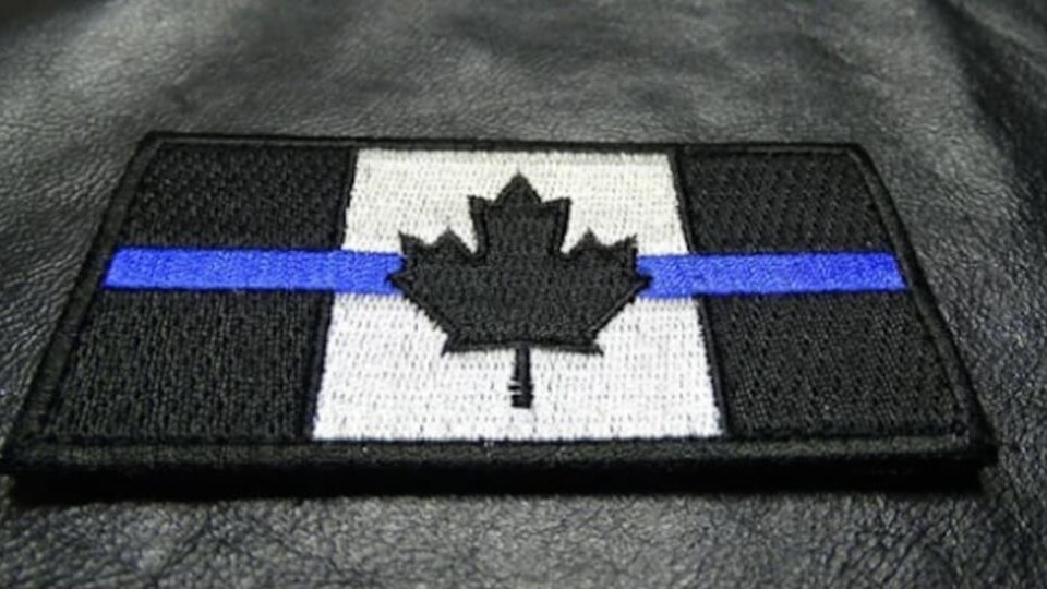 Un écusson avec le drapeau canadien et une ligne bleue.