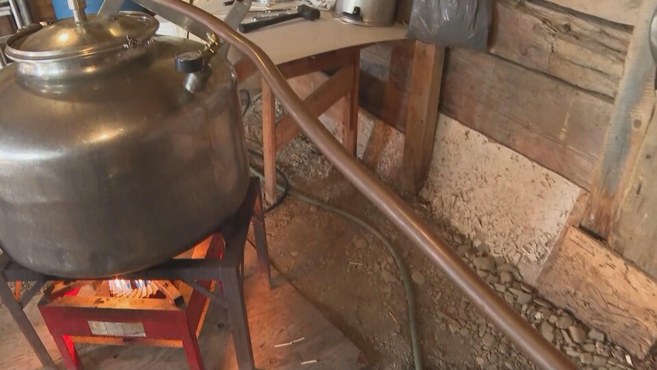 Un cruchon de métal auquel est relié un tube de métal sur un réchaud.