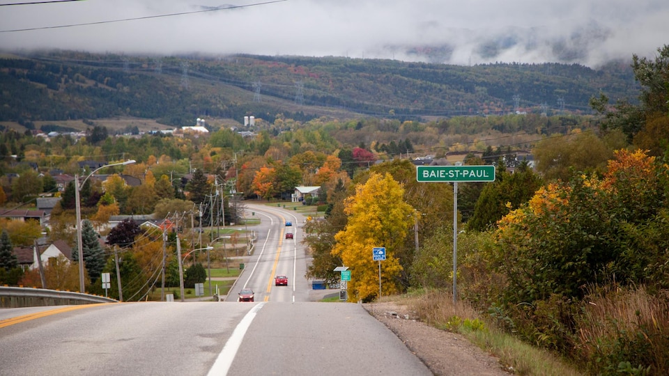Une pancarte de Baie-Saint-Paul, sur le bord d'une route à une voie dans chaque sens.