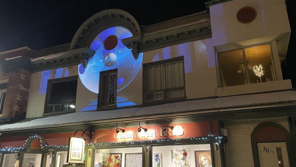 Une projection illumine l'étage supérieur d'un commerce.