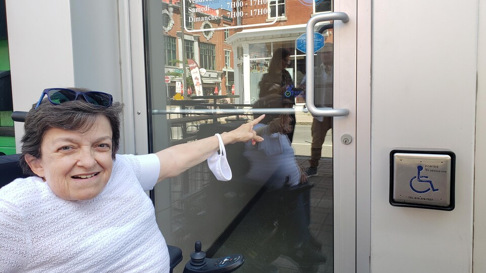 Judith Bastien pointe un autocollant Bail dans la vitrine d'une porte.