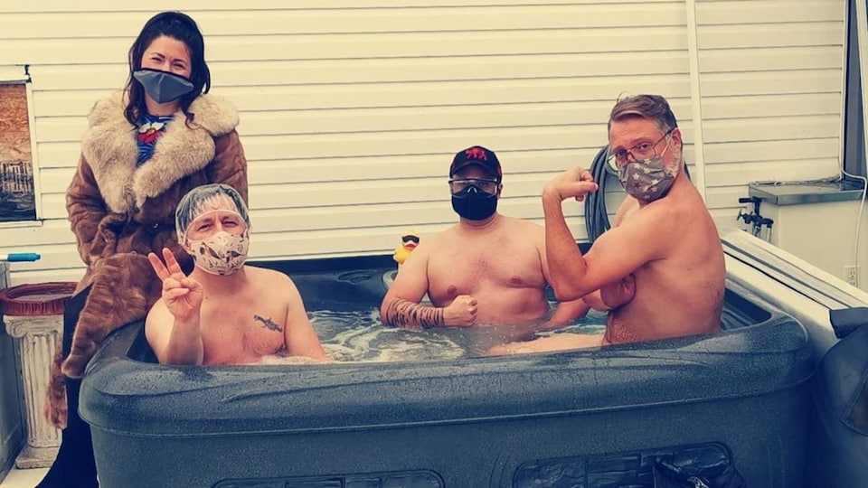 Trois hommes sont assis dans un spa et une femme s'ajoute à eux pour une photo officielle.