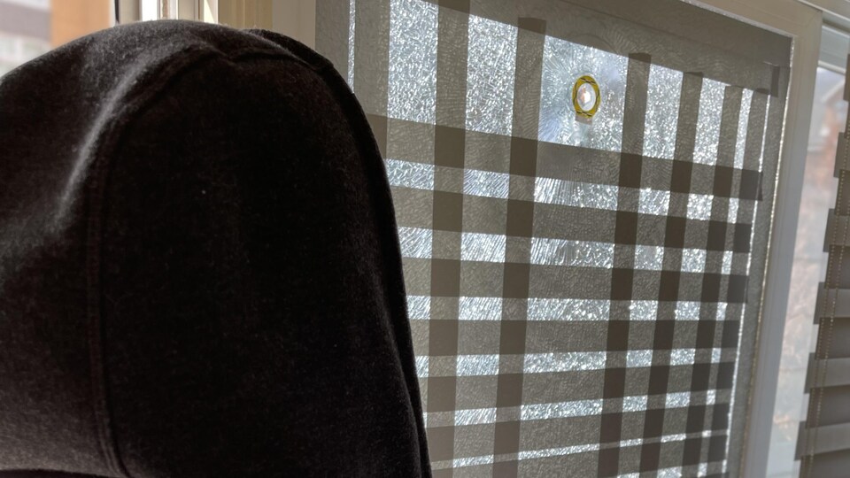 Jacqueline looks at the hole left by the bullet next to her stove.