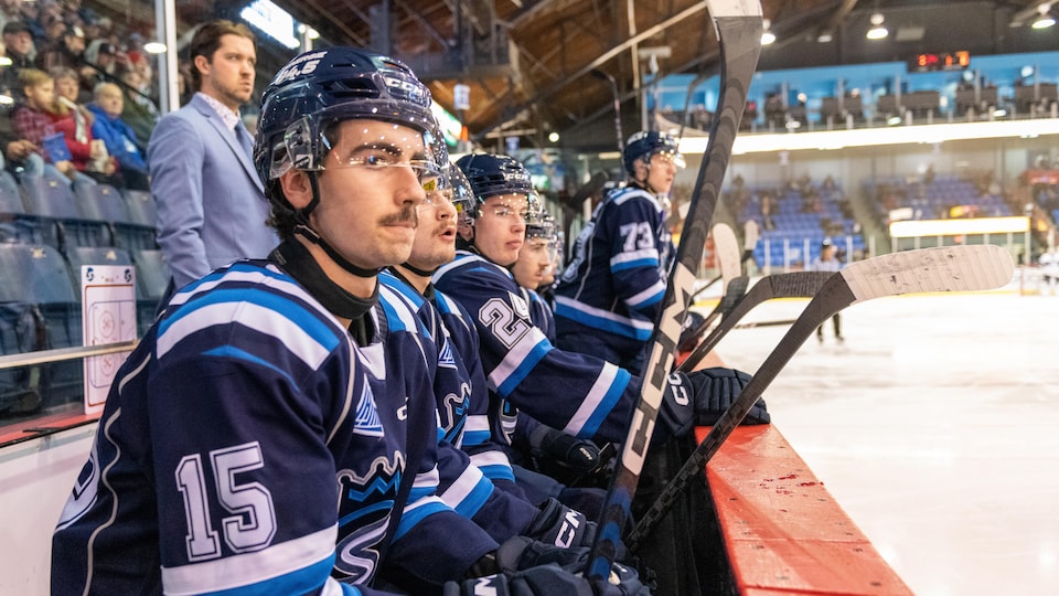Des joueurs des Saguenéens de Chicoutimi attendent de sauter sur la patinoire.