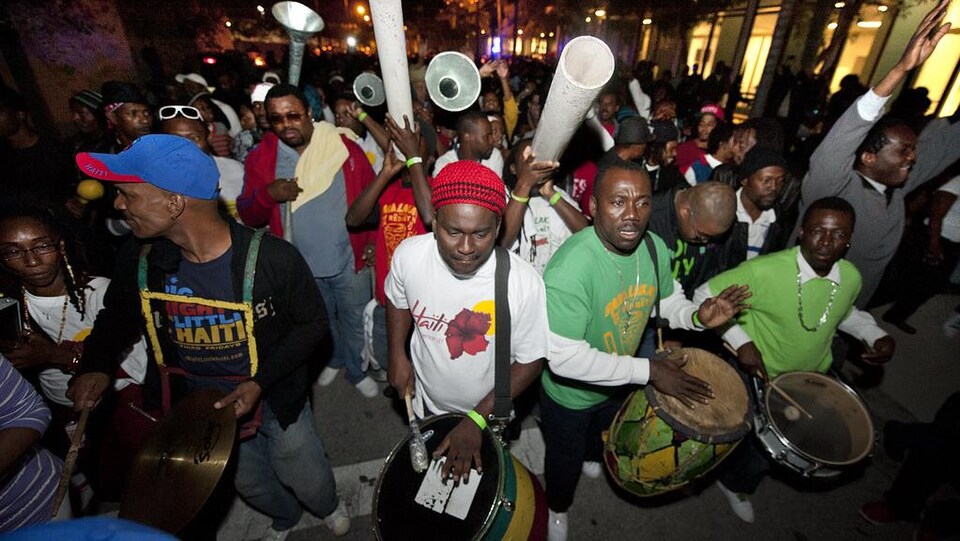 Des gens défilent dans la rue la nuit et jouent de la musique.