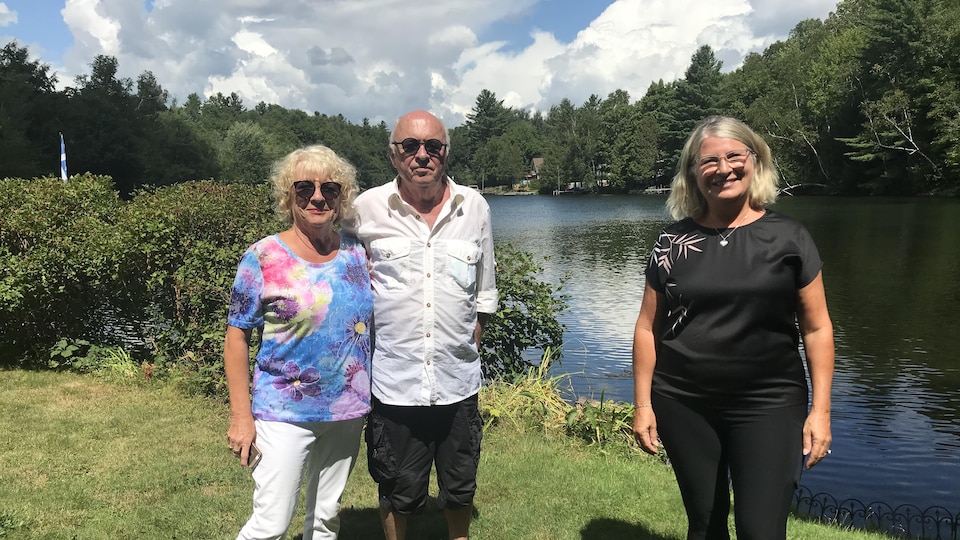 Trois personnes prennent la pose devant la rivière Magog, à Sherbrooke.