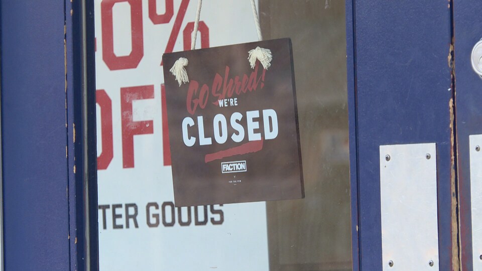 Une affiche « fermé » pend à la porte d'un commerce de la rue principale de Banff.
