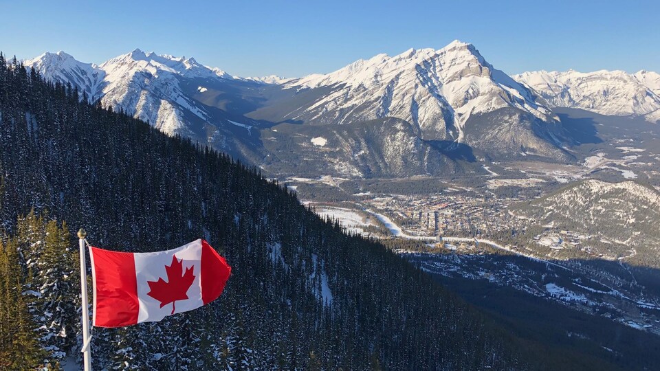 Vue de Banff du sommet du mont Sulphur, dans le parc national Banff. Un drapeau canadien flotte au premier plan.