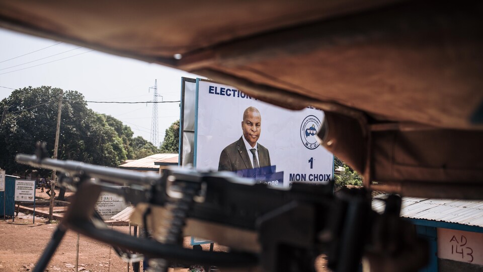 Un mitrailleuse est visible devant une affiche dans une rue de Bangui.