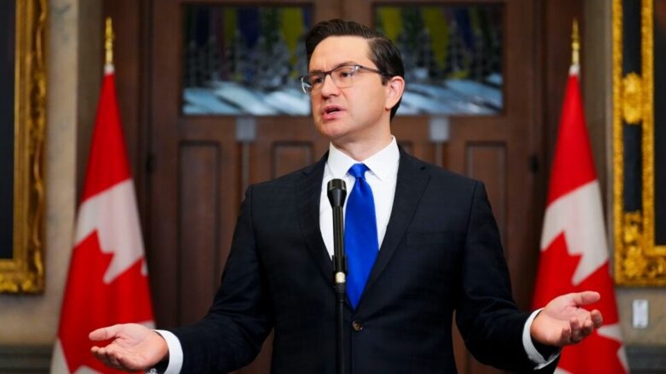 Le chef du Parti conservateur du Canada, Pierre Poilievre, parle au micro devant des drapeaux canadiens.