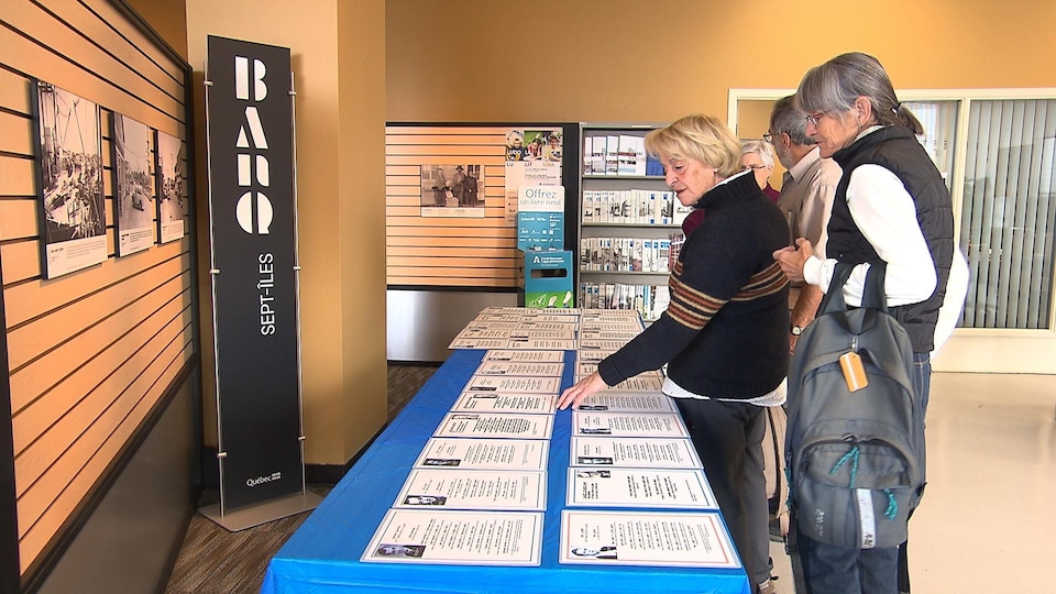 Des visiteurs devant une table remplie d'archives