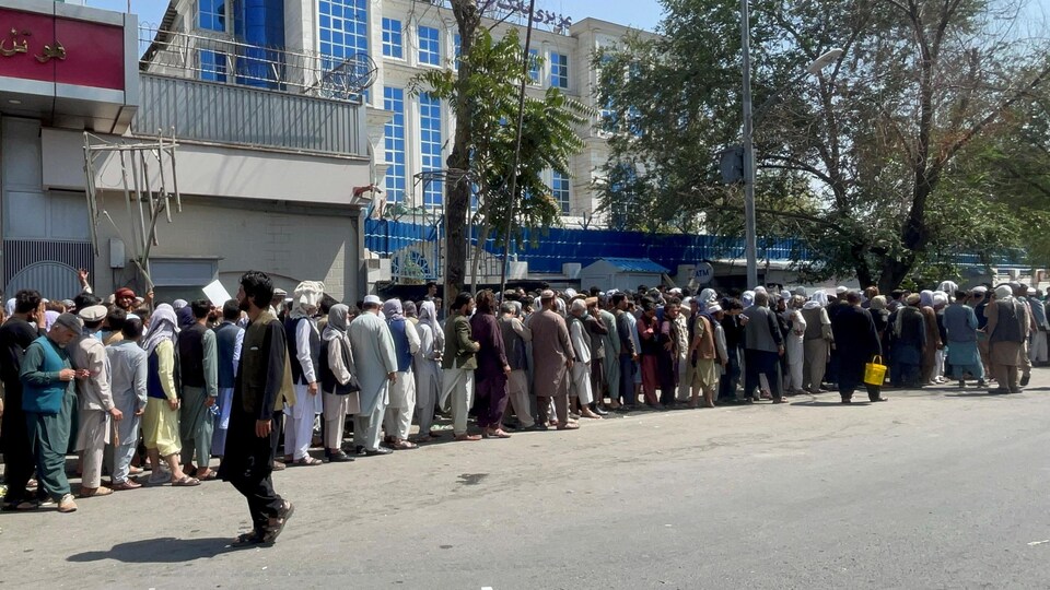 Une longue file d'Afghans dans une rue. 