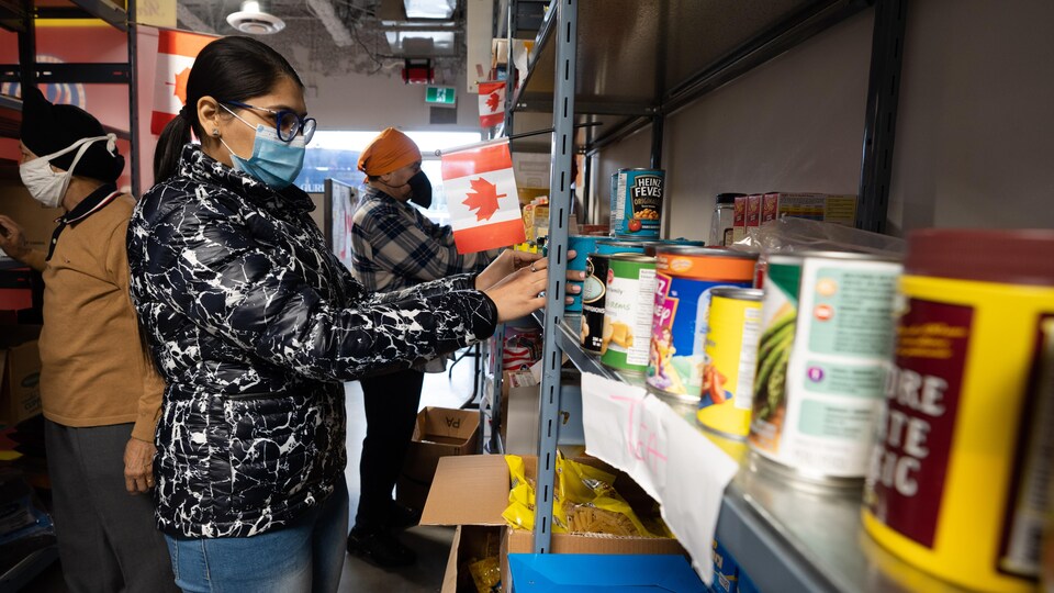 Des bénévoles placent des aliments sur les tablettes de la banque alimentaire Guru Nanak à Surrey, en Colombie-Britannique.