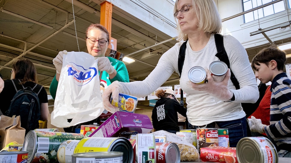 Des bénévoles s'attellent à trier des boîtes de conserves et d'autres aliments.