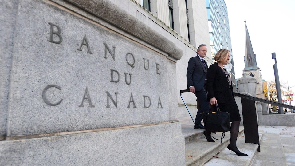 Stephen Poloz et Carolyn Wilkins descendent des marches devant l'immeuble de la Banque du Canada.
