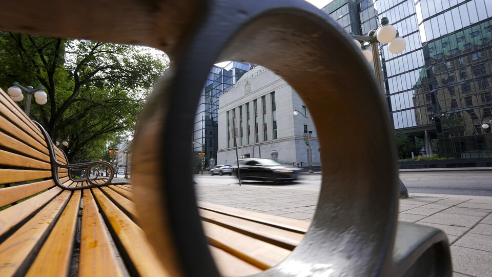 La Banque du Canada, vue à travers l'appui-bras d'un banc public.