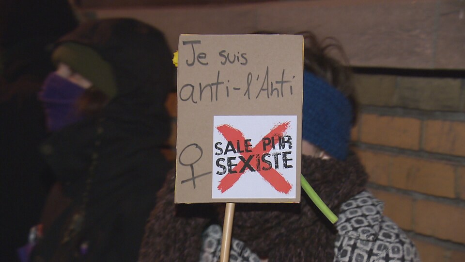 Une manifestante dénonce le bar l'Anti avec son affiche.