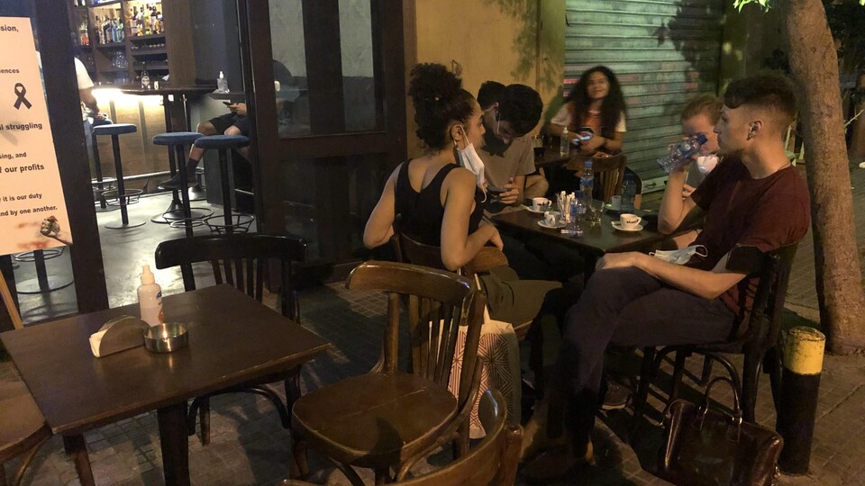 Cinq personnes assises à une table sur une terrasse.