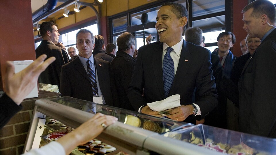 Barack Obama sourit devant un comptoir à biscuits. 