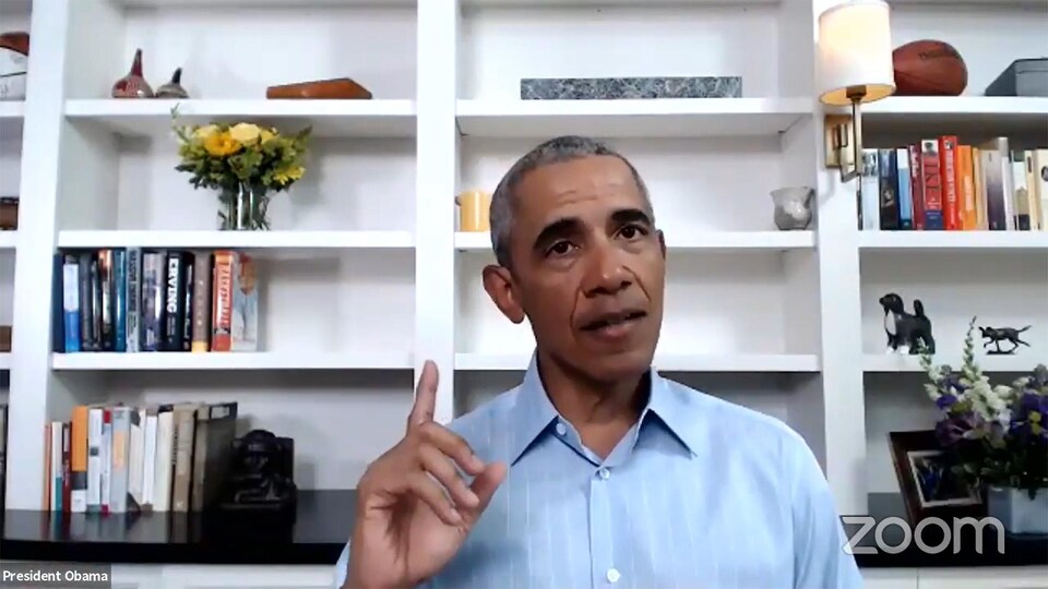 Barack Obama, un doigt en l'air, parle à la caméra devant une bibliothèque murale.