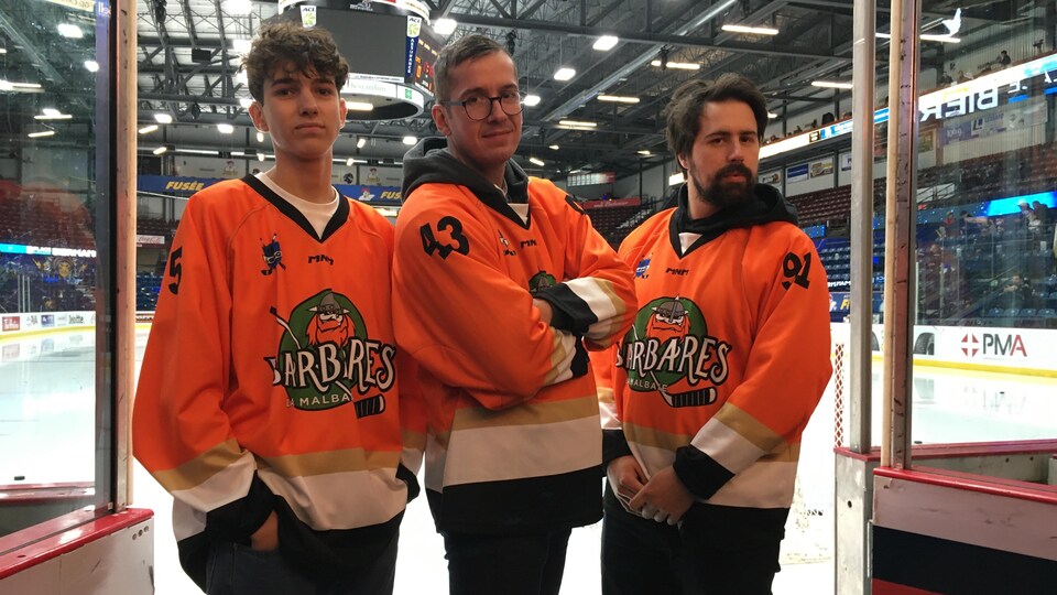 Trois hommes en maillot de sport dans un aréna.