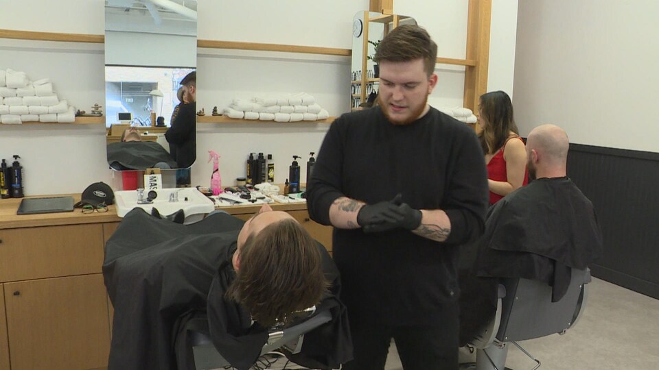 Un barbier s'apprête à tailler la barbe et les cheveux d'un client.