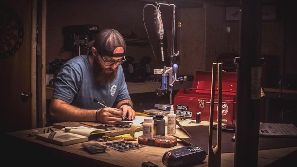 Sébastien Landry est assis et mesure des morceaux de fer dans son atelier.