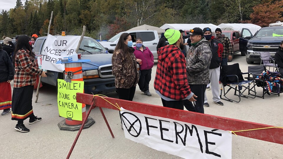 Des manifestants près d'une barrière indiquant Fermé.