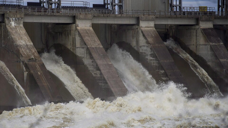 De l'eau sort des vannes d'un barrage hydroélectrique.