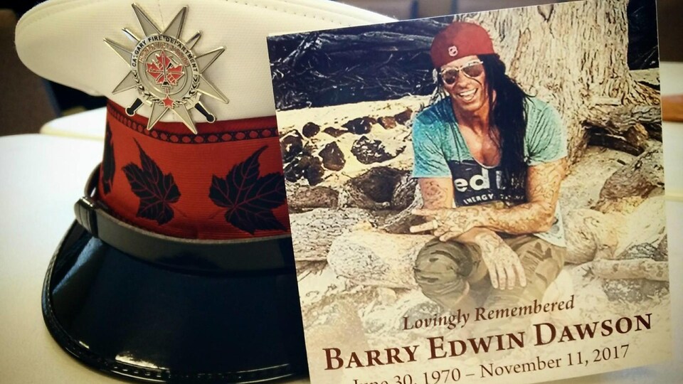 La photo d'un homme avec ses dates de naissance et de mort, posée à côté de sa casquette de pompier.