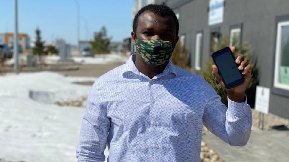 Barry Vopnu à l'extérieur, portant un masque et tenant son téléphone dans la main gauche.