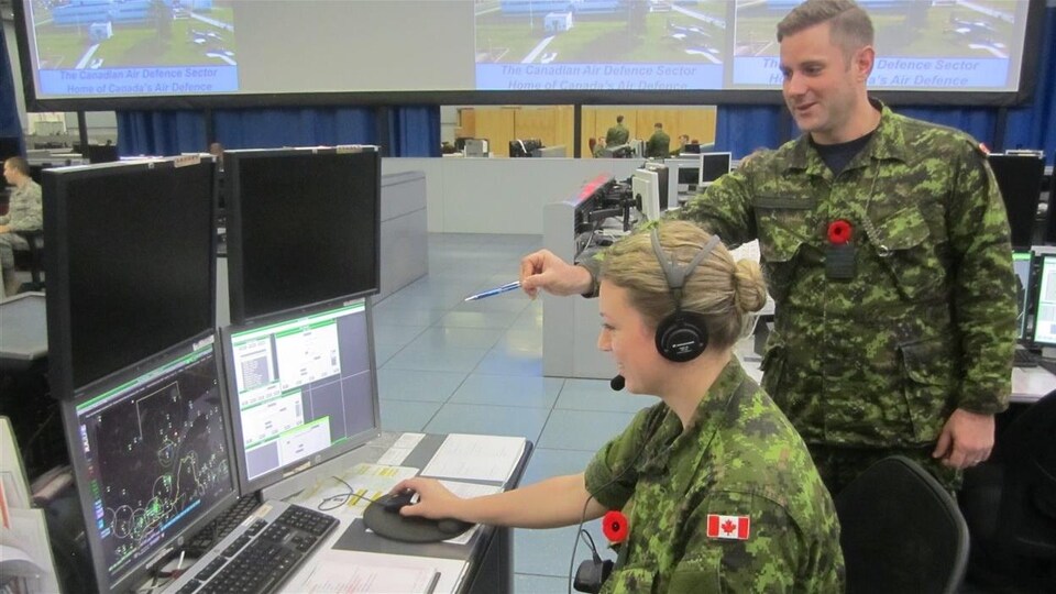 Deux militaires, un homme et une femme, dans la salle des opérations à North Bay