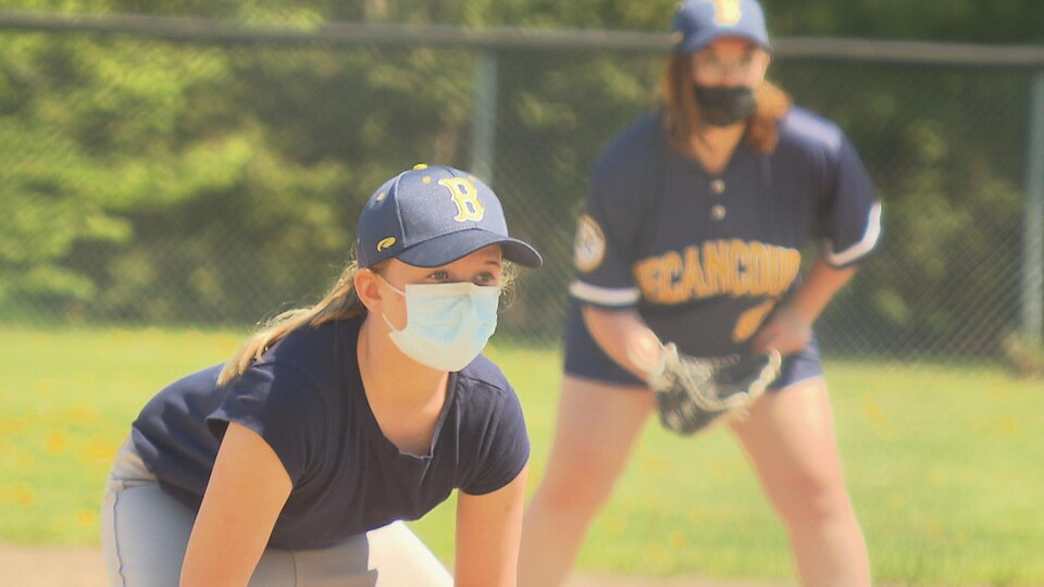 Sabryna Courey avec un gant de baseball à côté d'une jeune joueuse.