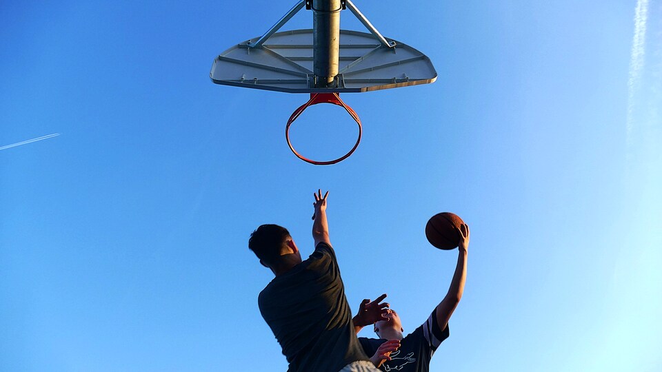 Deux hommes jouent au basketball.