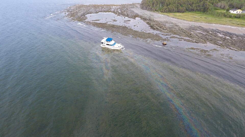 Une trace d'huile s'échappe du bateau échoué.