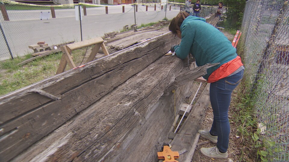 Une femme qui note sur une épave en bois.