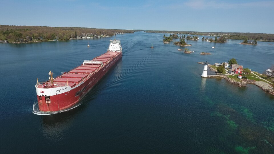 Photo d'un navire rouge sur une étendue d'eau en été.