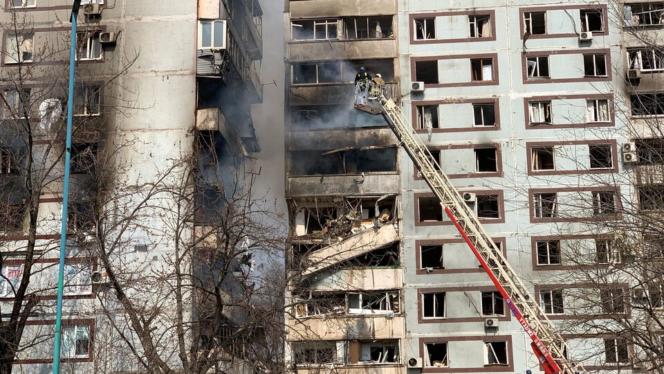 Des pompiers travaillent autour d'un bâtiment partiellement détruit.