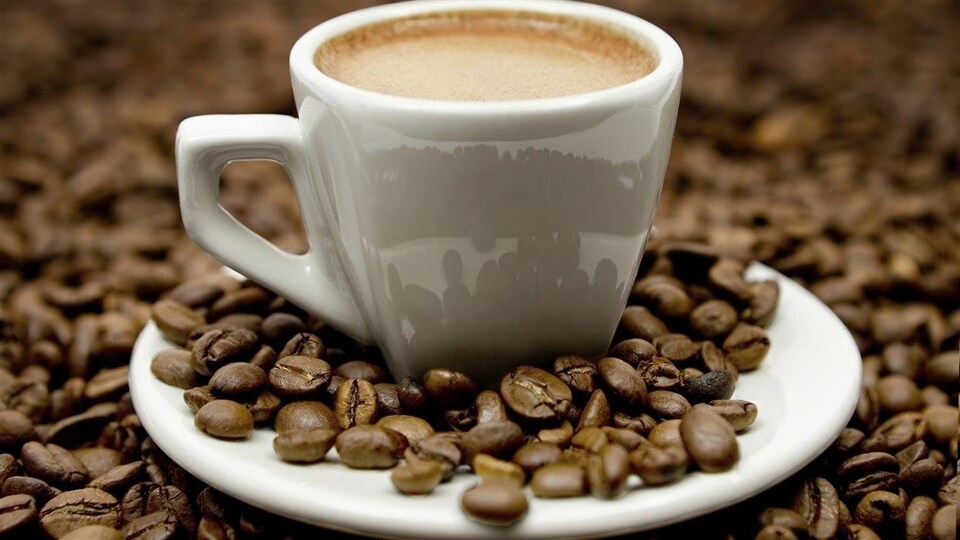 Une tasse de café au milieu de grains de café