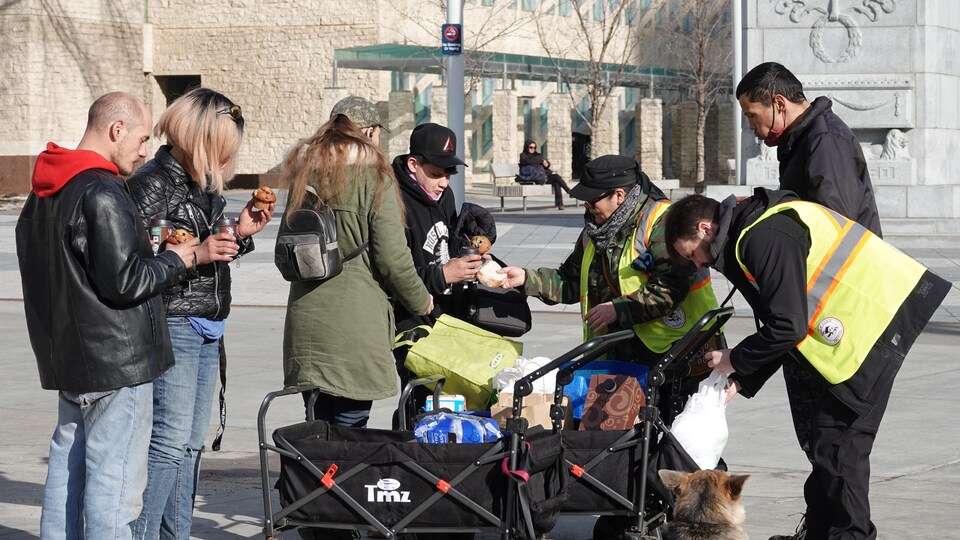 Un groupe de bénévoles et de résidents du centre-ville rassemblés autour de chariot remplis de nourriture.