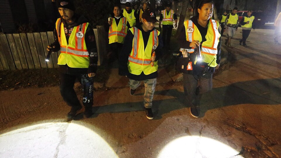 Un groupe d'homme et de femmes marchent dans une rue.