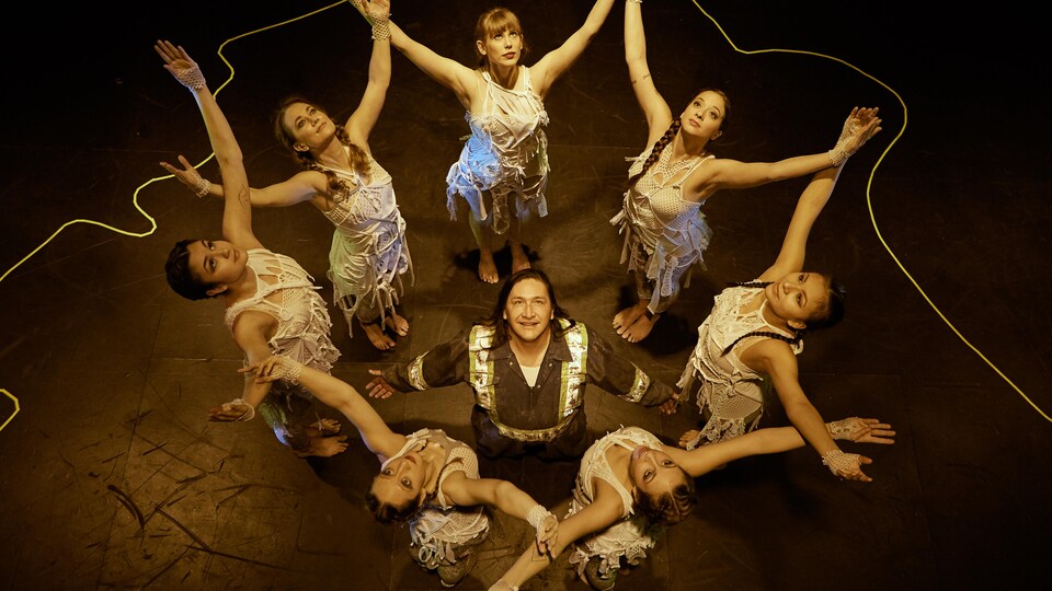 Un homme est entouré de femmes sur une scène de théâtre.