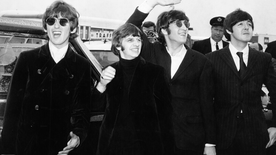 Les quatre membres du groupe The Beatles qui saluent leurs admirateurs et admiratrices en route vers l'aéroport de Boston, le 12 août 1966.