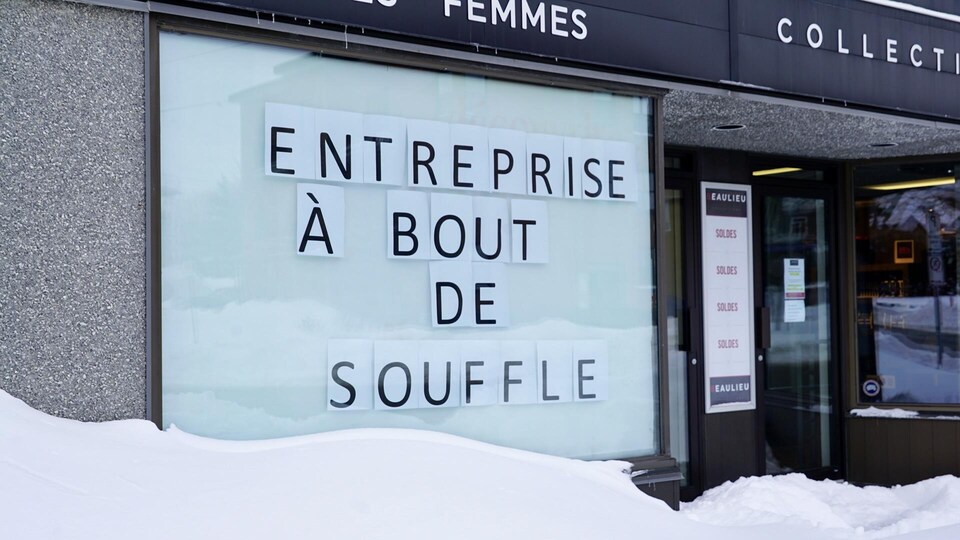 Devanture de commerce avec une affiche où il est inscrit "Entreprise à bout de souffle".