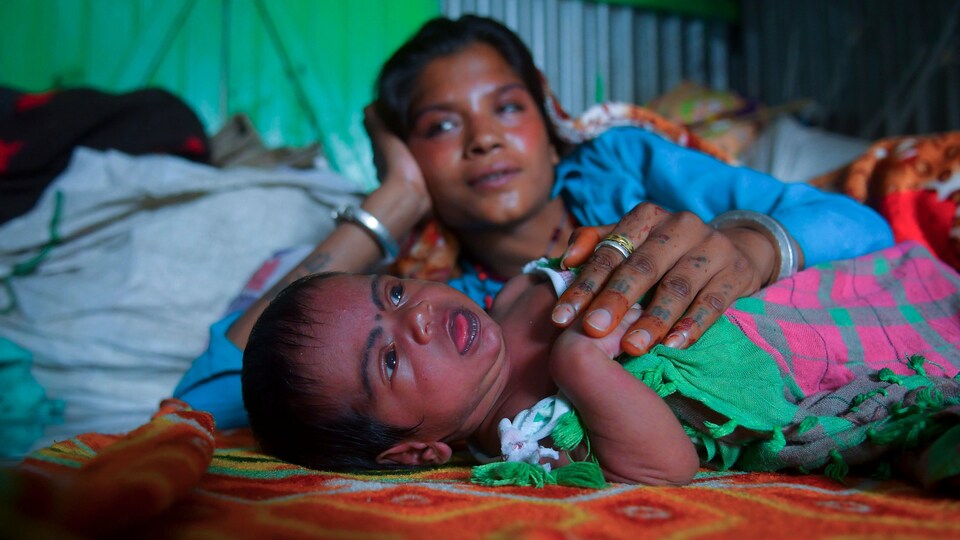 Une mère indienne est couchée près de son bébé.
