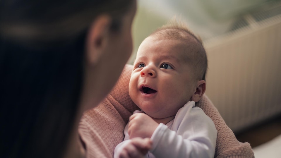 Un bébé regarde sa mère en souriant.
