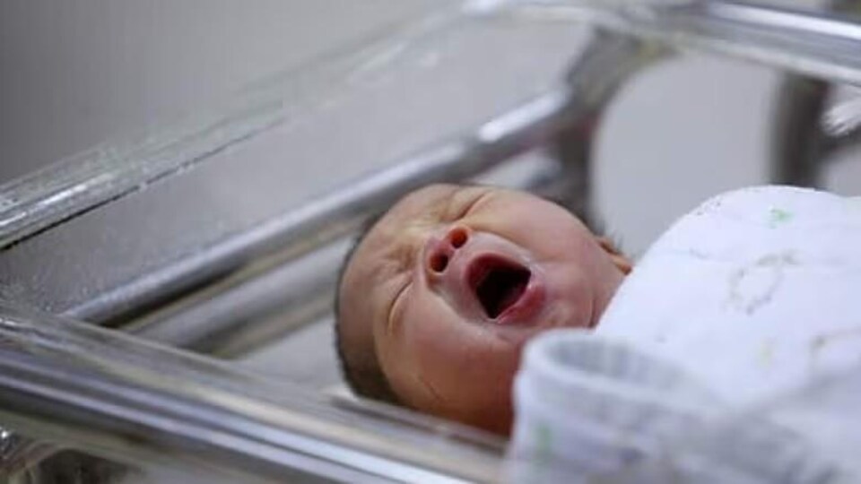 Un bébé pleure dans un lit à l'hôpital. 